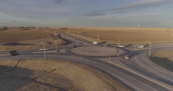 Cars and farm trucks navigate a modern roundabout far from the city. alt
