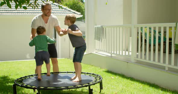 Father playing with kids on trampoline 4k alt