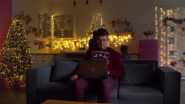 Man Working on Laptop in Room with Christmas Decorations