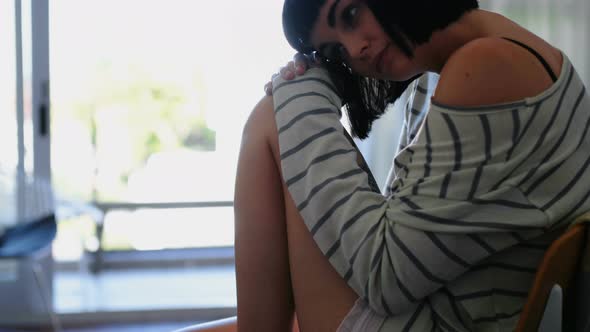 Woman sitting in living room at home alt