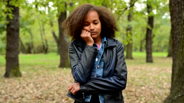Young Beautiful Sullen African Girl Is Bored in the Park alt