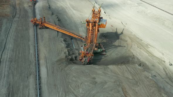 A Large Orange Bucketwheel Excavator in a Coal Mine Aerial View alt