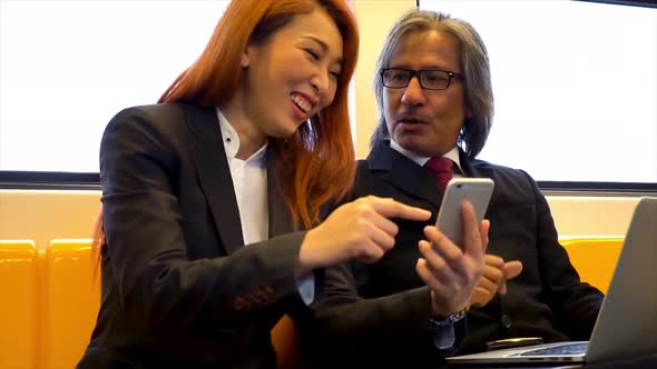 Business Woman Talking with Senior Smart Business Man with Smile and Laptop on Subway Train alt