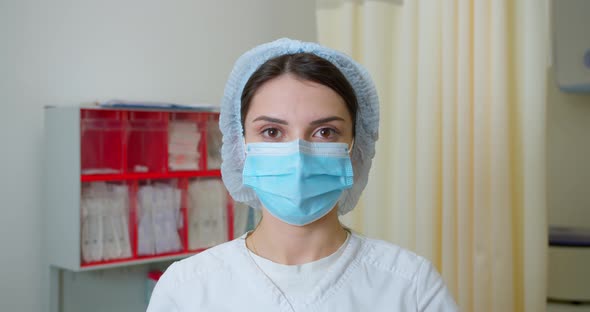 Portrait Shot of Female Medical Nurse in Medic Uniform Taking Surgical Mask Off Face Looking at