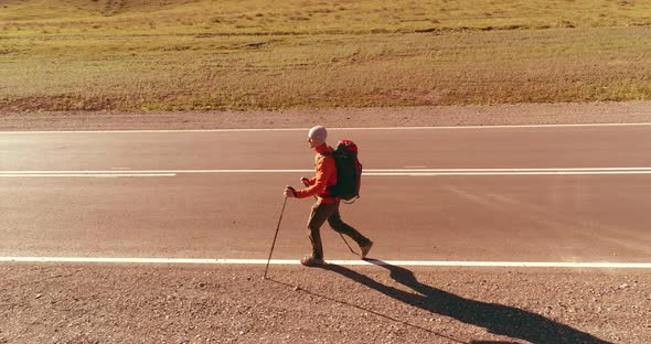 Flight Over Hitchhiker Tourist Walking on Asphalt Road alt