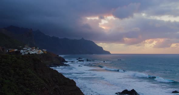 Silhouette Cliffs with Buildings of Little Tropical Town Almaciga in Sea Revealing Sunset alt