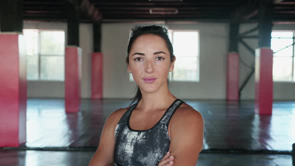 Young Female Fitness Guru Standing in Gym with Arms Crossed and Looking at Camera alt