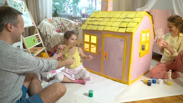Father Gives Happy Little Girl a Key To Her New Cardboard House. alt