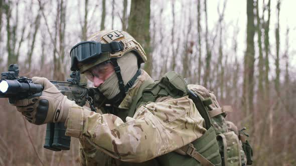 Armed Young Man in a Zone of Armed Conflict in Uniform Targeting with Assault Rifle Walking in alt