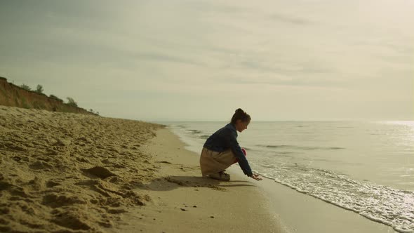 Little Kid Touching Sea Waves on Sunset Beach alt