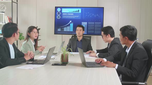 Young Asian Team Have Meeting In A Conference Room. They Share Opinions, Statistics Show On Tv alt