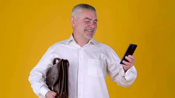 Portrait of Handsome adult businessman with briefcase uses smartphone texting messages