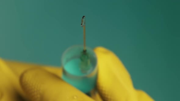 Syringe Needle with Liquid Dripping Drops of Medication in Doctor Hands alt