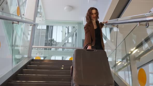 Slow Motion Footage of Young Elegant Woman Carrying Heavy Suitcase Up the Stairs at the Airport