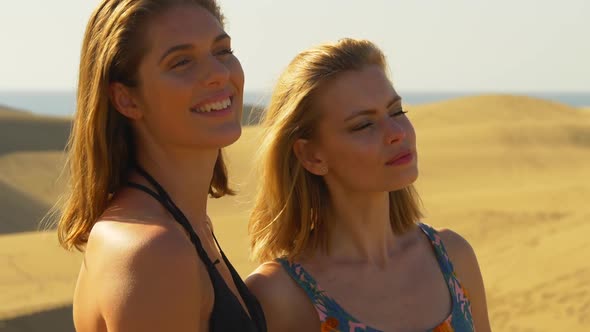 Gorgeous Female Models Looking at a Distance Sand Dunes in the Background alt