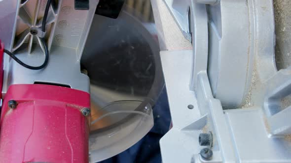 Vertical Shot Carpenter in Protective Gloves Cuts Off Wooden Oak Bar on Mitre Saw Closeup