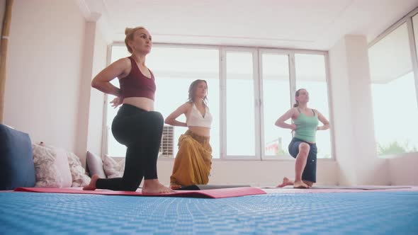 Three Women Standing on Yoga Mats on Their Knees and Doing the Exercises in the Studio alt