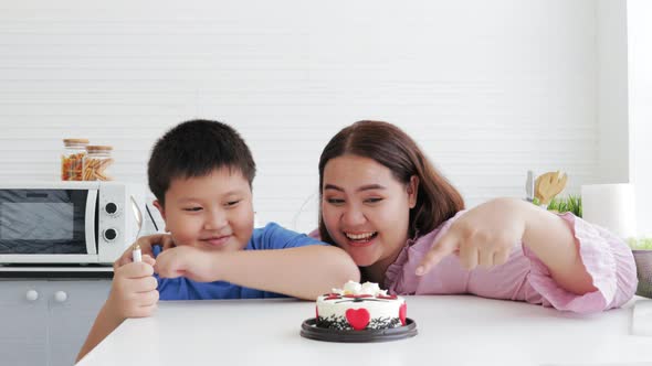 Asian Son and mom eating a cake together on her birthday