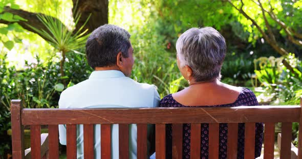 Senior couple talking in garden on a sunny day alt