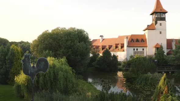 Weathercock in a garden with a pond next to a medieval castle,Czechia. alt