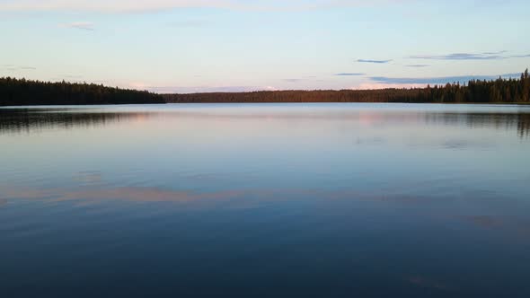 The open, calm waters of Cobb Lake at sunset in British Columbia, Canada. Low flying aerial shot alt