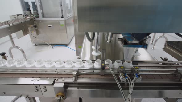 The Automated Packaging Machine is Filling the Containers with the Pills Moving on the Conveyor Line