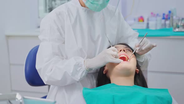 Asian young dentist wear mask, using medical instruments for oral care check up in dental clinic. alt