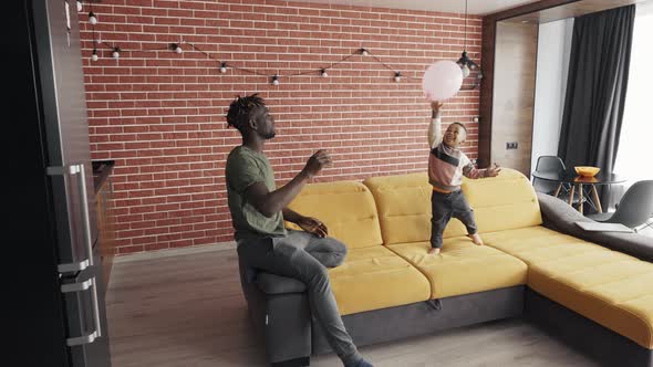 AfricanAmerican Father Playing with Little Boy Throwing Balloon to Each Other alt