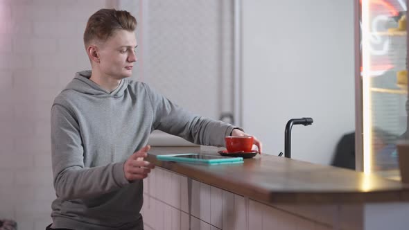 Unrecognizable Man Passing Coffee Cup for Student Surfing Internet on Tablet in Canteen alt