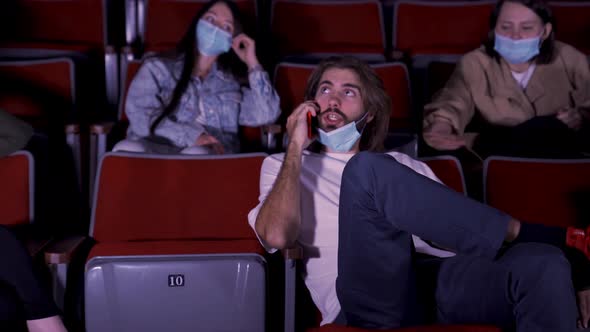 Confident young man talking on mobile phone in cinema, spectators looking angry alt