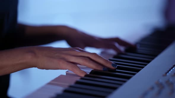 Female Musician is Playing Electric Piano at Home at Darkness Closeup of Hands Over Keys alt