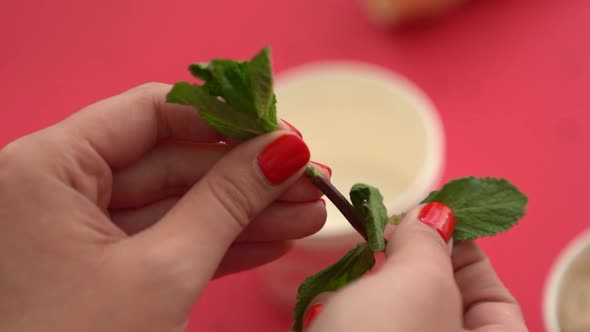 Close-up of plucking a mint leaf off the steam to use as a garnish on dessert. alt