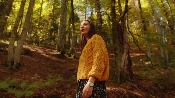 Young Woman Walks on the Scenic Autumn Forest Covered with Fallen Leaves and Colourful Foliage