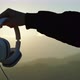 Hand holds music headphones in silhouette