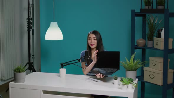 Asian Woman Reviewing Laptop Computer on Social Media Podcast alt