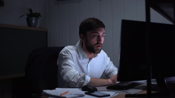 Photo of Serious Businesslike Man 20s in White Shirt Analyzing Data on Desktop Pc and Reacting alt