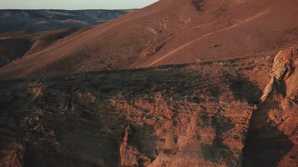 Drone View of Man on Motorbike Extremely Rides Across the Hills with Black Sea on Background 