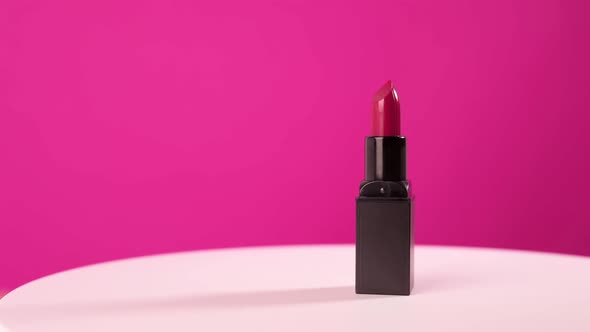 Lipstick in a Black Case Rotates on a Pink Background