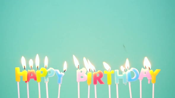 Happy Birthday Concept Made of Burning Colorful Candles on Blue or Turquoise Background alt