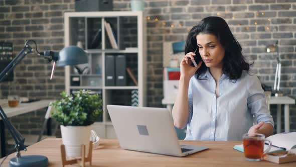 Angry Young Woman Speaking on Mobile Phone in Office Discussing Problems at Work alt