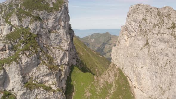 Flying between large rocks on mountain top and revealing beautiful valley alt
