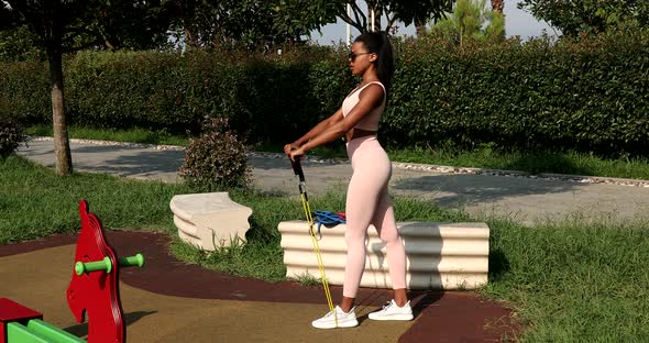 Black Athletic woman  on the sports ground training with elastic band.