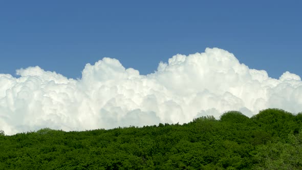 White Bubbling Clouds Fly Over a Mountain Forest. Beautiful Clouds Against the Blue Sky on the