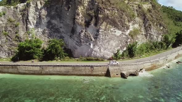 Aerial view of white car driving on coastline in Oslob, Philippines. alt