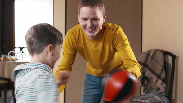 Happy dad helping his son to play with punching bag