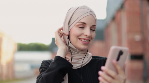 Portrait of Young Modern Arabian Woman Holding Mobile Phone and Listening the Music to Headphone alt