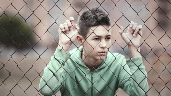 Refugee Boy Stands Alone Head Bowed Near the Fence Frustrated Boy Dropped Eyes Regrets the Act