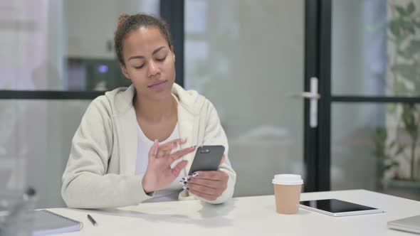 Successful African Woman Celebrating on Smartphone alt