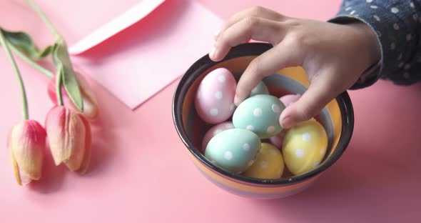 Easter Concept with Child Hand Pick Colorful Egg on Pink Background alt