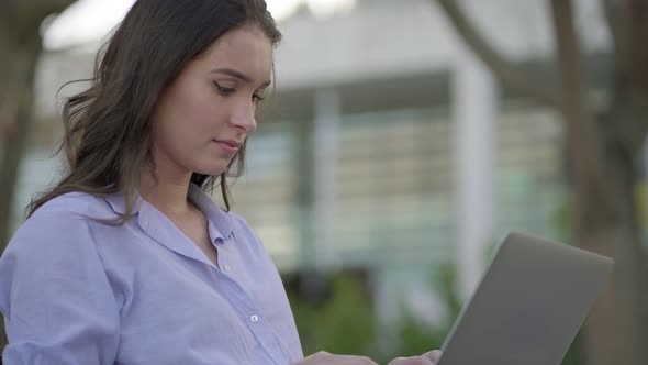 Side View of Pretty Caucasian Woman in Park Working on Laptop alt